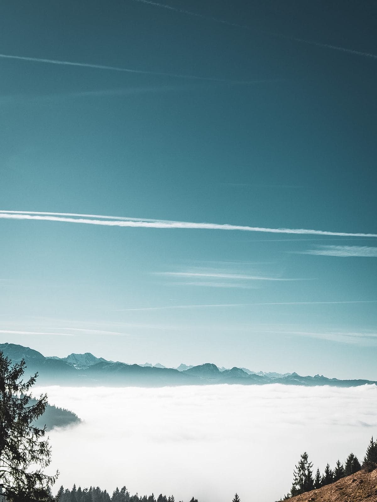 Nebelmeer unter blauem Himmel, Bergkette am Horizont