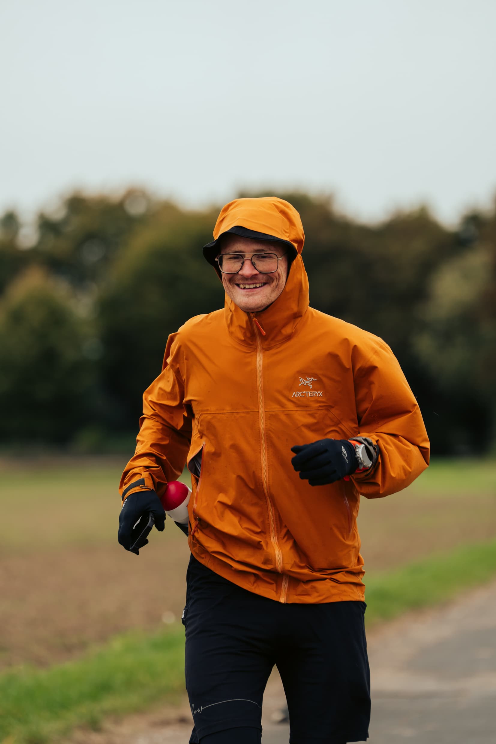 Pierre Biege lachend im Training, orange Regenjacke